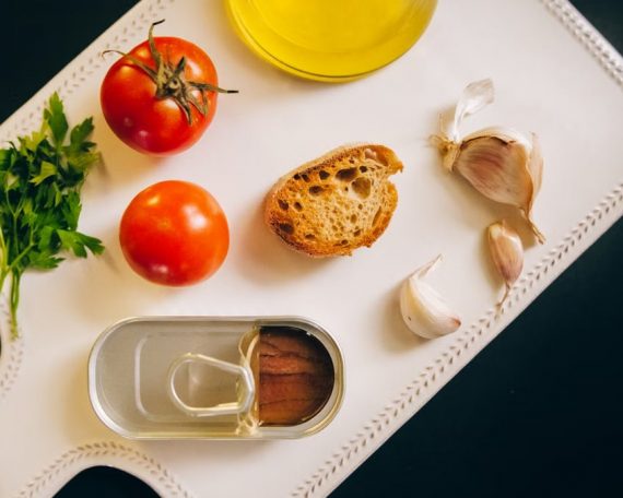 Fresh ingredients for making Catalán toast, including tomatoes, anchovies, and garlic.